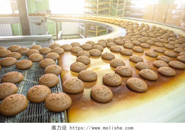 在面包机流水线上运作的面包烘焙生产线或传送带上有新鲜的甜饼干。糖果厂车间、工业食品生产设备机械.